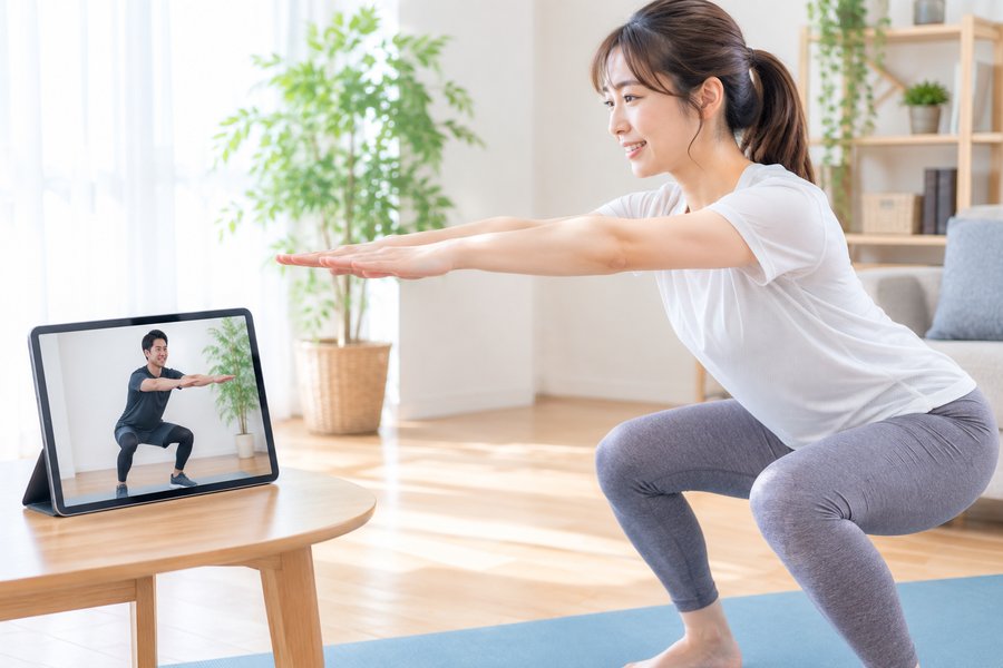 タブレット越しにトレーナーの指導を受けながらスクワットをする様子
